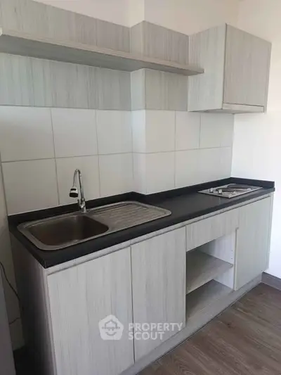 Modern kitchen with sleek cabinetry and stainless steel sink in a minimalist design.