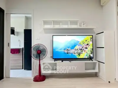 Modern living room with sleek TV setup and stylish fan, adjacent to a compact kitchen area.