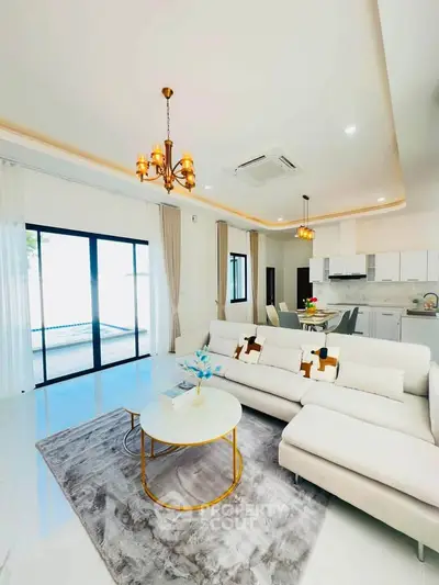 Luxurious modern living room with elegant decor and open kitchen layout, featuring plush seating and stylish lighting.