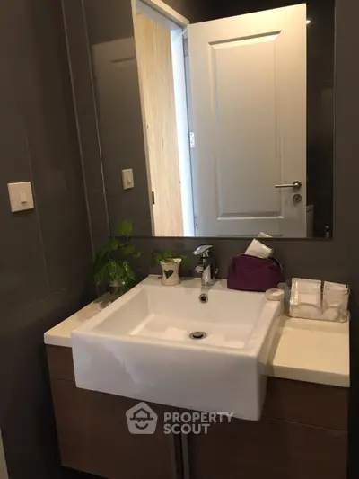 Modern bathroom with sleek sink and mirror, featuring contemporary design and elegant fixtures.