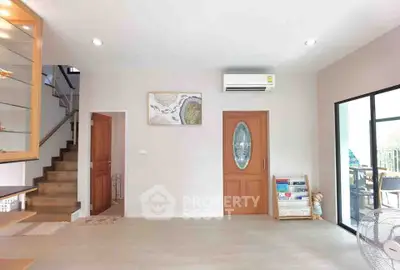 Bright living room with modern decor and air conditioning, featuring a staircase and glass door to balcony.