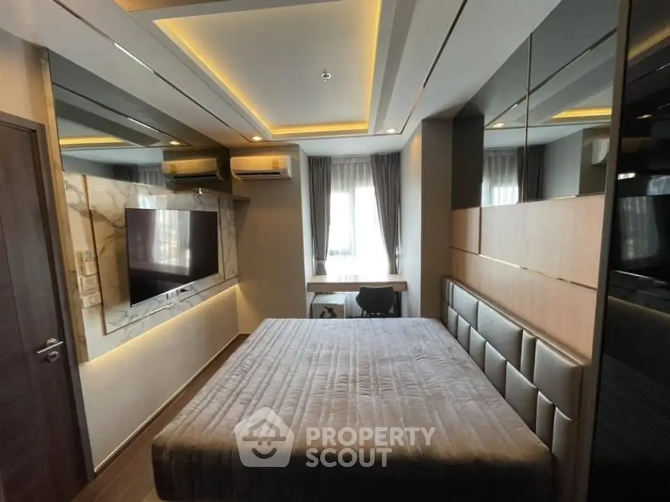 Modern bedroom with stylish decor, featuring a large bed, wall-mounted TV, and elegant lighting.