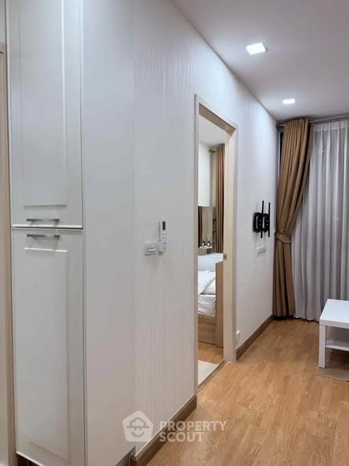 Modern apartment hallway with wooden flooring and elegant curtains leading to a cozy bedroom.
