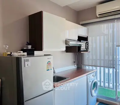 Modern kitchen with sleek cabinets, washing machine, and large window for natural light.