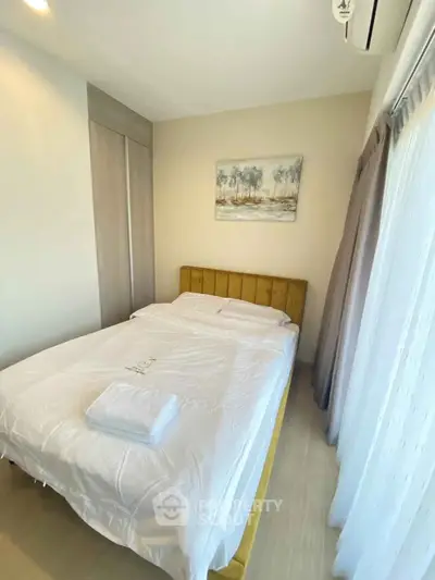Cozy bedroom with modern decor and natural light, featuring a comfortable bed and stylish artwork.