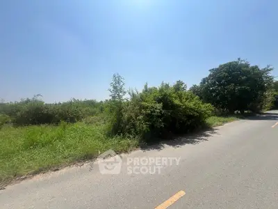 Expansive land plot with lush greenery and clear blue sky, ideal for development.