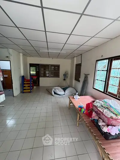 Spacious room with tiled floor and large windows, ideal for versatile use in a residential property.