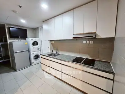 Modern kitchen with sleek cabinets, washing machine, and fridge in a stylish apartment.