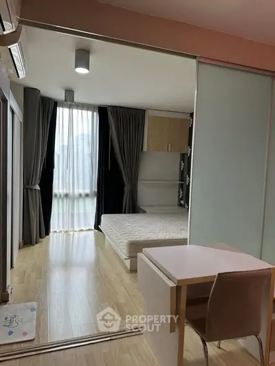 Modern studio apartment with wooden flooring and large window