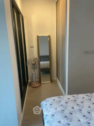 Cozy bedroom with standing mirror and fan, perfect for minimalist living.