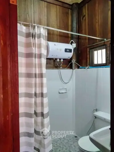 Cozy rustic bathroom with wooden walls and modern shower heater, perfect for a warm and inviting home.