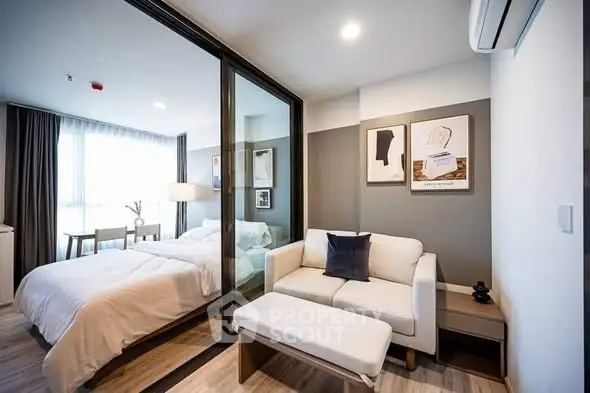 Modern studio apartment with glass partition separating bedroom and living area.