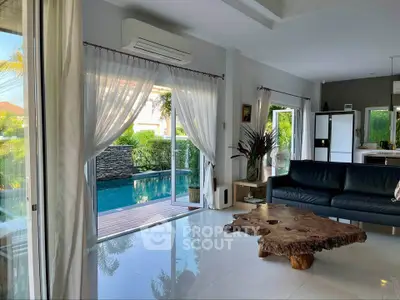 Luxurious living room with pool view, featuring elegant decor and natural light.