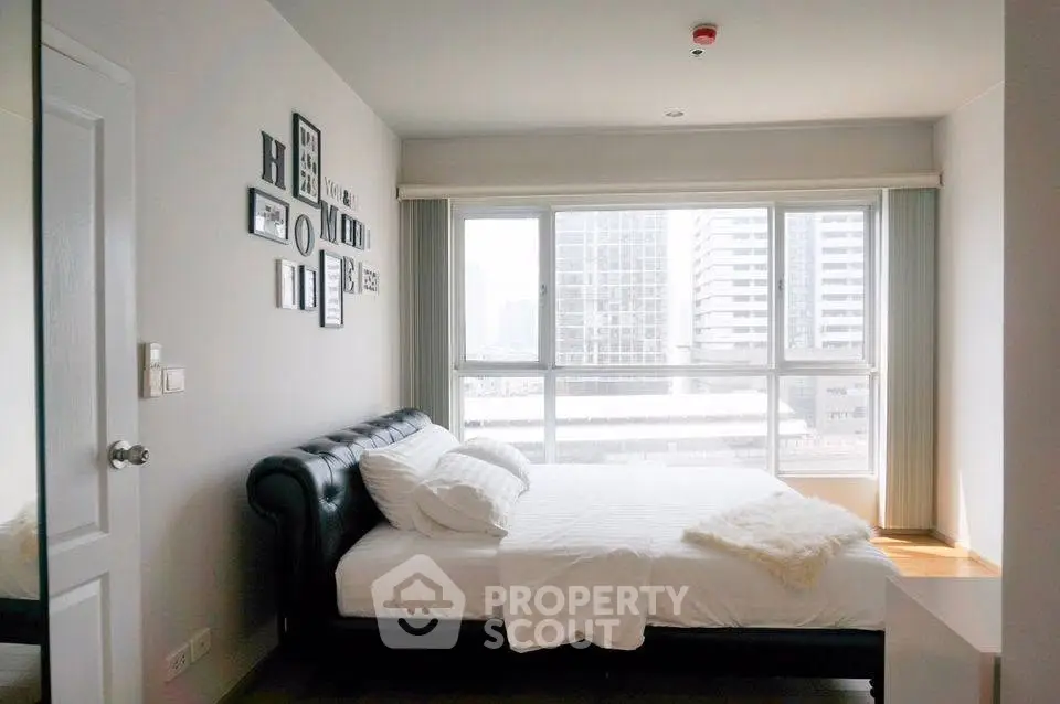 Modern bedroom with large window and city view in high-rise apartment