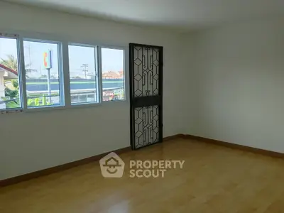 Spacious empty room with large windows and secure door, ideal for customization.