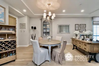 Elegant dining room with stylish decor and wooden flooring, featuring a wine rack and chandelier lighting.