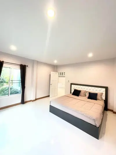 Spacious bedroom with modern decor and large window offering natural light