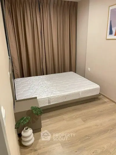 Cozy bedroom with minimalist decor and wooden flooring, featuring a comfortable bed and elegant curtains.