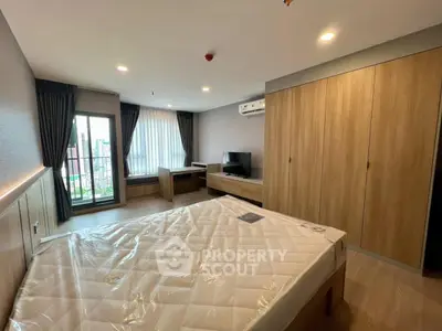 Spacious bedroom with modern furnishings and city view from large window.