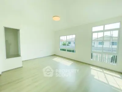 Spacious sunlit living room with large windows and modern flooring in a serene neighborhood.