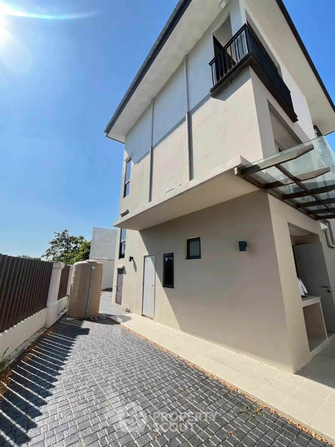 Modern three-story building with sleek design and spacious outdoor area under clear blue sky.