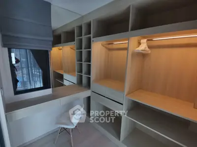 Spacious walk-in closet with modern shelving and seating area in a stylish apartment.