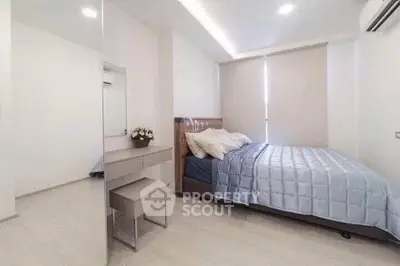Modern bedroom with stylish decor and ample natural light, featuring a cozy bed and sleek furniture.