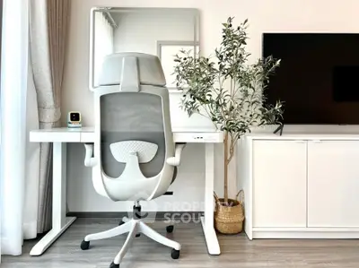 Modern home office setup with ergonomic chair, sleek desk, and large TV in a bright, minimalist room.
