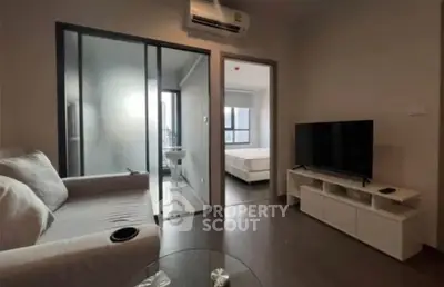 Modern living room with sleek furniture and open layout, featuring a cozy sofa and flat-screen TV.