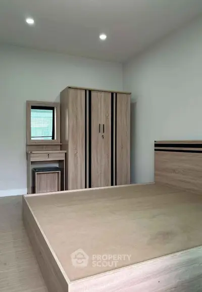 Modern minimalist bedroom with wooden furniture and ample natural light.