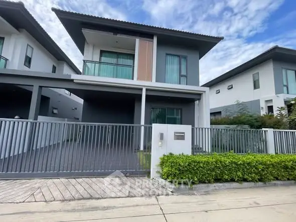 Modern two-story house with sleek design and gated entrance in a suburban neighborhood.