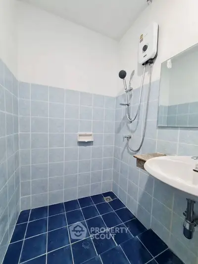 Compact bathroom with blue tiles and modern shower setup