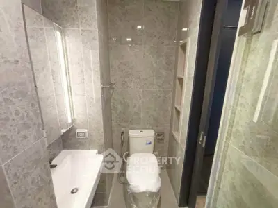 Modern bathroom with sleek fixtures and marble tiles, featuring a compact design for efficient space use.
