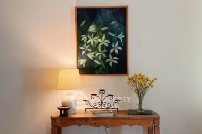 Charming interior with elegant wooden table, stylish lamp, and floral artwork, perfect for cozy living spaces.