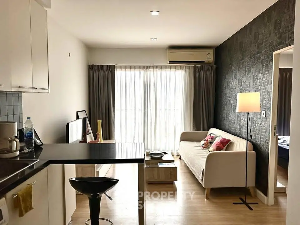 Modern living room with stylish decor and natural light, featuring a cozy sofa and open kitchen layout.