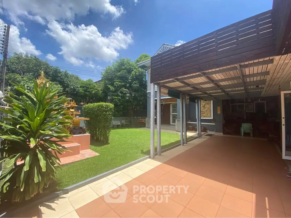 Charming outdoor patio with lush garden and covered seating area, perfect for relaxation and entertaining.