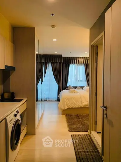 Modern apartment interior with cozy bedroom and in-unit laundry, featuring elegant curtains and warm lighting.