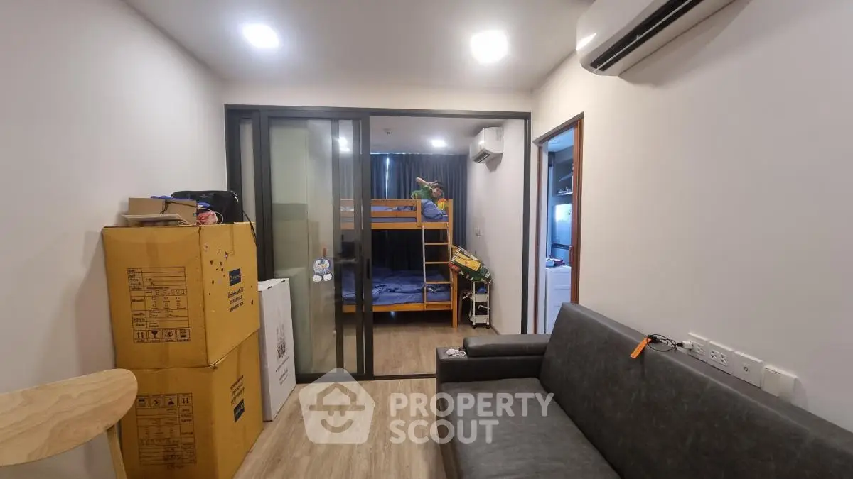 Modern compact living room with sliding glass doors and bunk beds in view