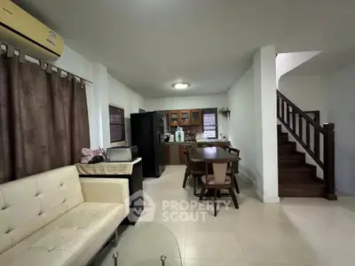 Spacious open-plan living area with modern kitchen and dining space, featuring a cozy seating area and elegant staircase.