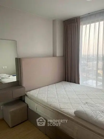 Modern bedroom with large window and neutral decor in a high-rise apartment.