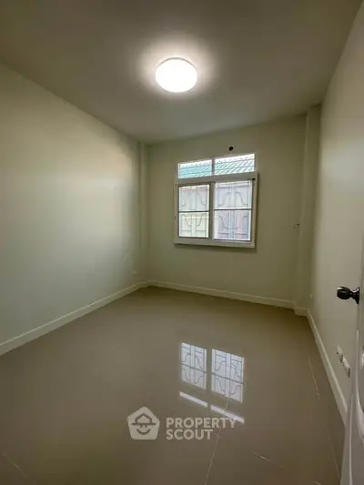 Spacious empty room with glossy tiled floor and large window, perfect for customization.