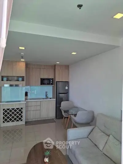 Modern open-layout kitchen and living room with sleek furniture and appliances.