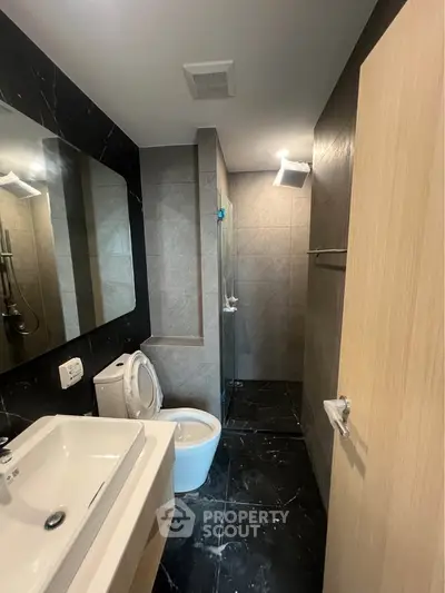 Modern bathroom with sleek design, featuring a glass shower and stylish fixtures.