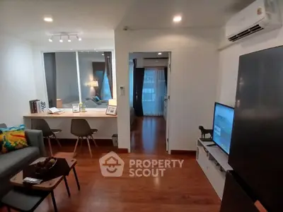 Modern living room with wooden flooring, cozy seating, and stylish decor in a contemporary apartment.