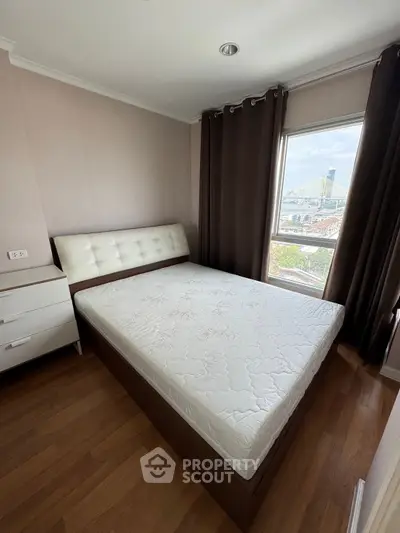 Cozy bedroom with city view, featuring a comfortable bed and elegant curtains.