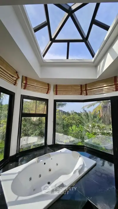 Luxurious bathroom with skylight and jacuzzi overlooking lush greenery