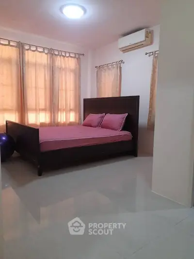 Spacious bedroom with large windows and air conditioning, featuring a stylish bed and elegant curtains.
