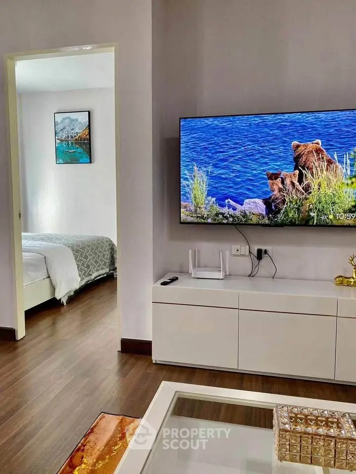 Modern living room with wall-mounted TV and view into cozy bedroom