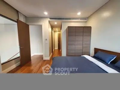 Spacious modern bedroom with wooden flooring and sleek wardrobe design.