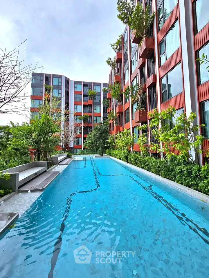 Luxurious modern apartment building with stunning outdoor pool and lush greenery.